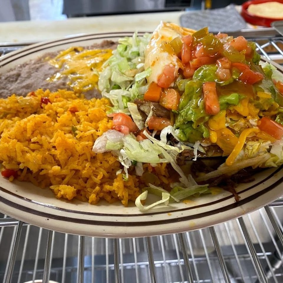 A Jalisco Mexican Grill plate with a large burrito, rice, and refried beans with melted cheese.