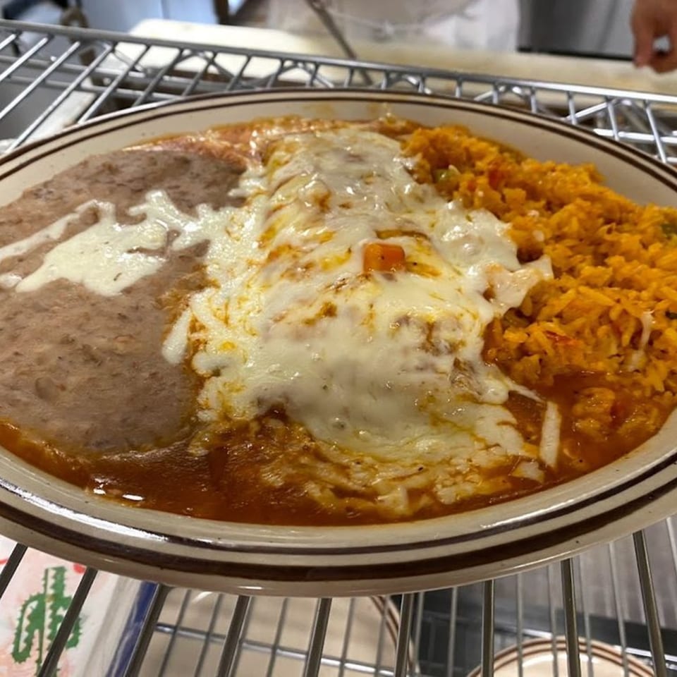 A plate of Jalisco Mexican Grill's enchiladas covered in melted cheese, with refried beans and rice.
